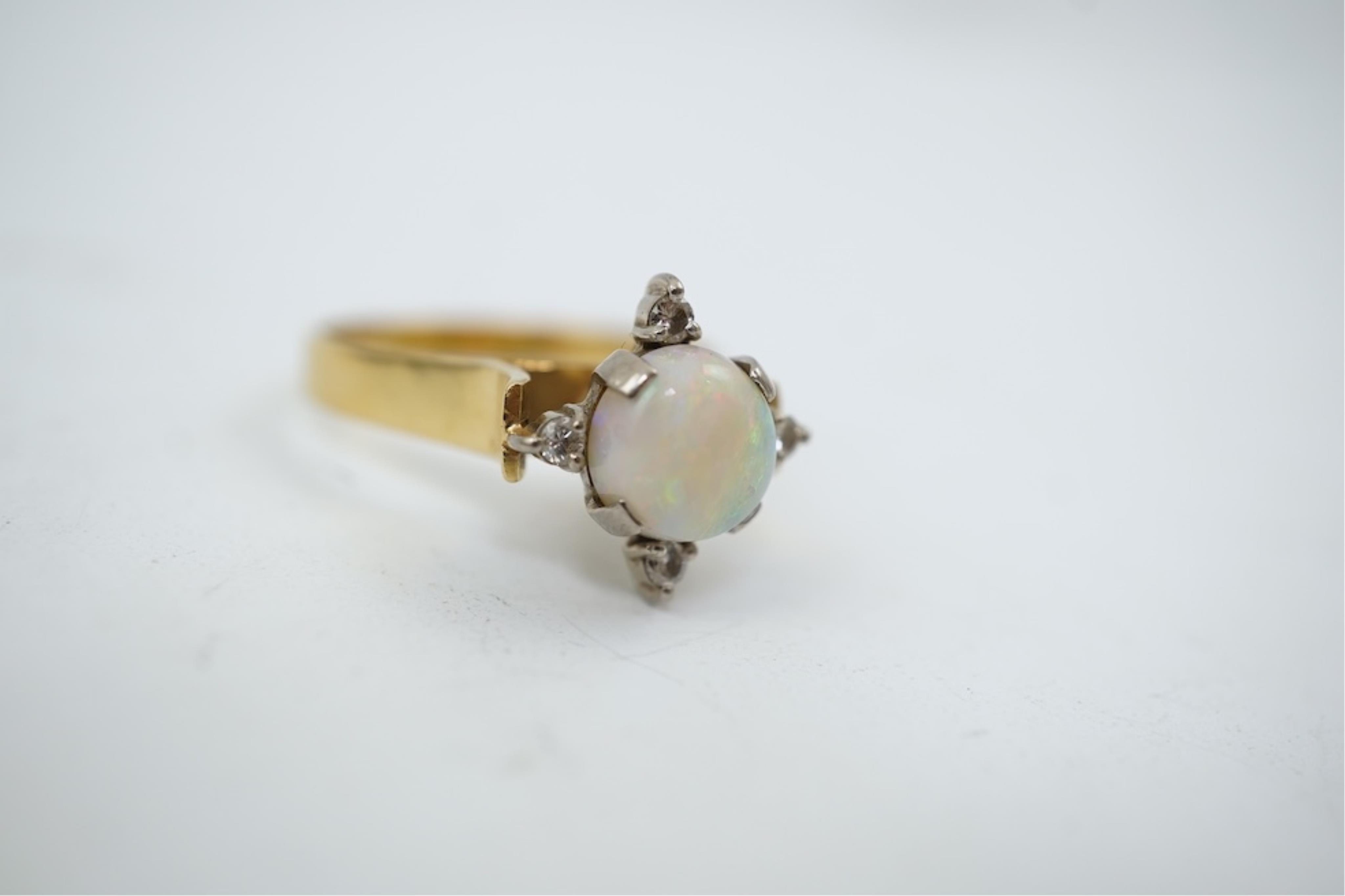 A yellow metal (stamped 18), single stone white opal and four stone diamond chip set ring, size P/Q, gross weight 3.8 grams.